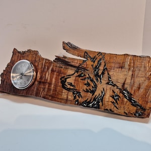 May include: A wooden clock with a wolf design burned into the wood. The clock is made from a piece of reclaimed wood with a natural wood finish.