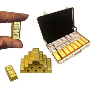May include: A silver briefcase filled with stacks of gold bars and fake money. The gold bars are labeled "999.9 Fine Gold" and "Met Wt 200g".