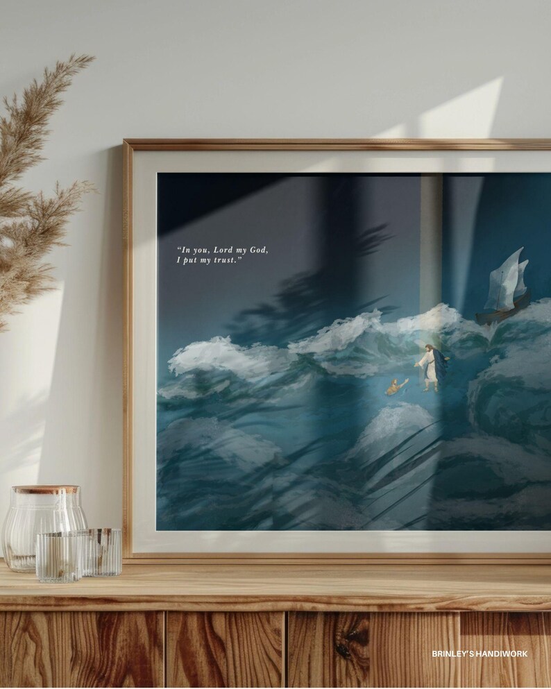May include: Framed art print featuring a religious scene with a figure walking on water, a boat, and a small animal. The artwork is set against a backdrop of turbulent waves and a bright sky. The text "In you, Lord my God, I put my trust." is visible. The frame is a light brown color.