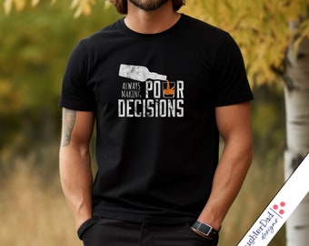 May include: A black t-shirt with a white graphic design that says "Always Making Poor Decisions" with a cartoon image of a bottle pouring alcohol into a glass.
