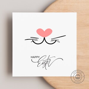 May include: A printable card featuring a pink heart and black whiskers, with the text "Happy Easter" in black cursive.