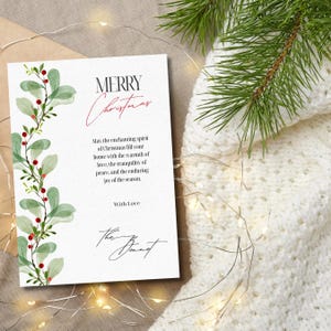 May include: A white rectangular greeting card featuring a watercolor illustration of green mistletoe leaves and red berries along the left side. The text reads Merry Christmas, May the enchanting spirit of Christmas fill your home, With Love, The Bennet.
