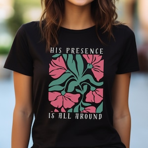 High-quality soft-style t-shirt made with ethically grown cotton. Beautiful floral graphic with a stylish font that says His presence is all around. Available in various colors. Female model wears black.