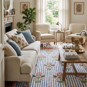 May include: A living room scene featuring a striped rug with floral patterns in red, green, and blue. The rug is placed in front of a beige sofa and two armchairs. The room has a neutral color palette with natural light.