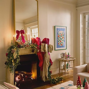 Puede incluir: Un sal&oacute;n festivo con una chimenea decorada, con un gran espejo con marco dorado. La repisa de la chimenea est&aacute; adornada con guirnaldas, velas y grandes lazos rosas. Una mesa auxiliar tiene bebidas y una impresi&oacute;n enmarcada.