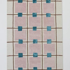 Puede incluir: Alfombra rectangular con fondo crema y un patr&oacute;n de cuadr&iacute;cula de l&iacute;neas marrones. Cuadrados rosas dispuestos en filas y columnas, cada uno con un cuadrado turquesa en el centro. Dise&ntilde;o geom&eacute;trico moderno.