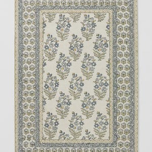 May include: Rectangular floral patterned rug with a cream background and a border. The rug features repeating clusters of blue and gray flowers with yellow accents. The border has a repeating floral design in shades of gray and green.