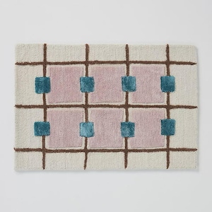 Puede incluir: Alfombra rectangular con fondo crema, l&iacute;neas de cuadr&iacute;cula marrones y cuadrados rosas. Cuadrados turquesa se colocan dentro de los cuadrados rosas. La alfombra tiene un aspecto texturizado y tejido, adecuada para una sala de estar o dormitorio.