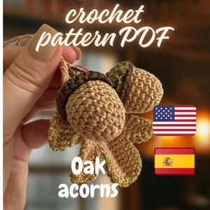 May include: Crocheted oak acorns with gold accents. The image includes the text "crochet pattern PDF" and "Oak acorns". The acorns are a light brown color with a darker brown cap. The leaves have gold trim.