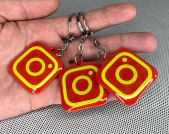 May include: Three red and yellow Instagram logo keychains with silver key rings.