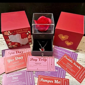 Pode incluir: Uma caixa vermelha com o texto "I love you forever" e uma rosa vermelha dentro. A caixa é cercada por cupons rosa e vermelhos com textos como "Spa Day", "Yes Day", "Day Trip", "Compliments Day", "Cuddle Sesh" e "Pamper Me".