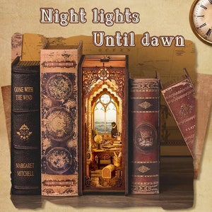 May include: A miniature diorama of a room with a window, a desk, and a chair. The diorama is made to look like a book with a carved wooden cover. The text "Night lights Until dawn" is written above the diorama.