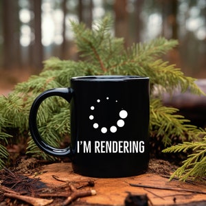May include: A black coffee mug with a white loading icon and the text "I'm Rendering" on it. The mug is sitting on a tree stump in a forest.