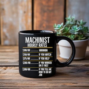 May include: Black coffee mug with a white graphic that reads "Machinist Hourly Rates" with a list of hourly rates and corresponding descriptions. The rates are $100/hr, $150/hr, $175/hr, $200/hr, and $399/hr.