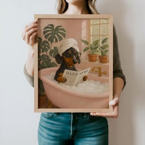 May include: Framed art print featuring a dachshund in a bathtub, wearing a towel and glasses, reading a newspaper. The print has a pink and green color scheme, with plants and a window in the background. The newspaper reads "DAILY NEWS".