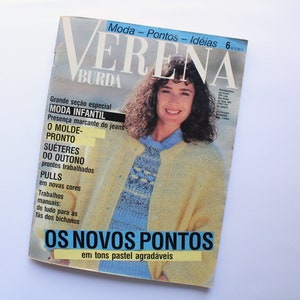 May include: A magazine cover featuring a woman wearing a yellow knitted sweater with a blue and white pattern. The magazine is titled "Verena" and the cover text reads "Os Novos Pontos em tons pastel agradáveis".