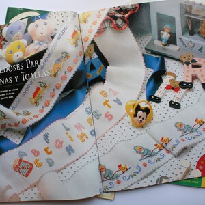 May include: An open magazine with a white background and colorful embroidery designs. The magazine cover features the word "Hope" in large, colorful letters. The magazine is titled "Entre doses para sabanas y toallas" and features a variety of embroidery patterns, including letters, animals, and flowers.