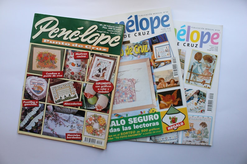 May include: Three copies of the Spanish language magazine "Pen&eacute;lope Punto de Cruz" featuring cross-stitch patterns. The magazine covers feature images of kitchen motifs, angels, and children.