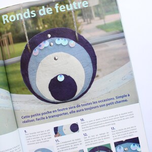 May include: A step-by-step guide on how to make a felt pouch with a circular design. The pouch is made with three layers of felt in blue, white, and dark blue. The pouch is decorated with iridescent sequins and has a button closure. The text in the image reads "Ronds de feutre" and "Cette petite poche en feutre sera de toutes les occasions. Simple &agrave; r&eacute;aliser, facile &agrave; transporter, elle aura toujours son petit charme."