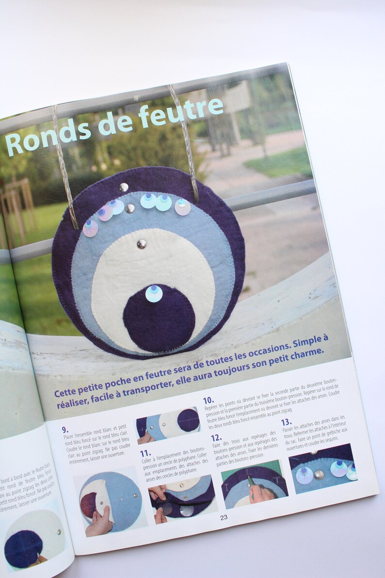 May include: A step-by-step guide on how to make a felt pouch with a circular design. The pouch is made with three layers of felt in blue, white, and dark blue. The pouch is decorated with iridescent sequins and has a button closure. The text in the image reads "Ronds de feutre" and "Cette petite poche en feutre sera de toutes les occasions. Simple &agrave; r&eacute;aliser, facile &agrave; transporter, elle aura toujours son petit charme."