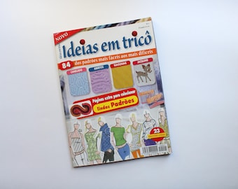 May include: A magazine cover with the title "Ideias em tricô" in red and white text. The cover features a variety of knitting patterns, including a deer, a diagonal pattern, and a cable knit pattern. The magazine is a new release and features 84 patterns.