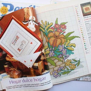 May include: A magazine page with a cross-stitch pattern for a floral design. The pattern is titled "Hogar dulce hogar" which translates to "Home sweet home".