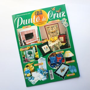May include: A green magazine cover with the title "Casa Punto de Cruz" and images of cross-stitch projects, including a mirror, pillows, a lamp, and a pair of slippers.