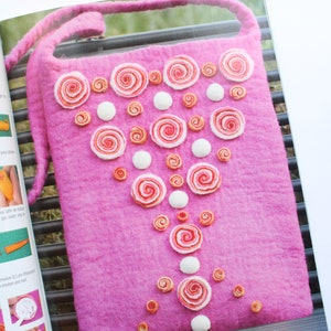 May include: A pink felt bag with a white strap and a design of white and pink felt circles arranged in a triangular pattern.