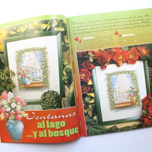 May include: Two framed cross-stitch patterns featuring windows with floral arrangements. The text "Ventanas al lago...y al bosque" is printed on the page.