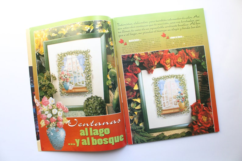 May include: Two framed cross-stitch patterns featuring windows with floral arrangements. The text "Ventanas al lago...y al bosque" is printed on the page.