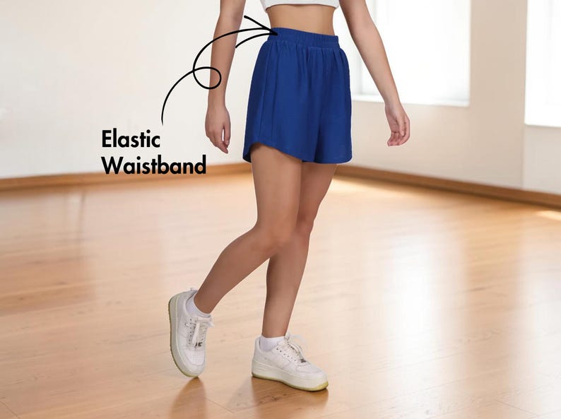 May include: Royal blue shorts with an elastic waistband. The shorts are paired with white sneakers. The text "Elastic Waistband" is visible in the image.