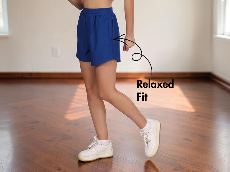 May include: Royal blue shorts with a relaxed fit. The shorts are paired with white sneakers. The text "Relaxed Fit" is next to the shorts. The shorts are made of a lightweight material.