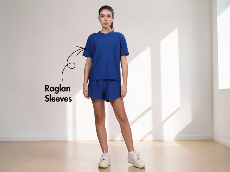 Puede incluir: Una mujer con un conjunto de camiseta y pantal&oacute;n corto azul a juego, con mangas ragl&aacute;n. La camiseta tiene cuello redondo y mangas cortas. El pantal&oacute;n corto es de un tono azul similar. Lleva zapatillas blancas. El texto "Raglan Sleeves" est&aacute; en la imagen.