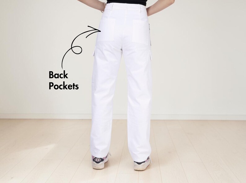 May include: White cargo pants featuring a high-waisted design, straight legs, and two large back pockets. A black arrow points to the back pockets with the text "Back Pockets" written in black next to the arrow, highlighting the pocket placement.