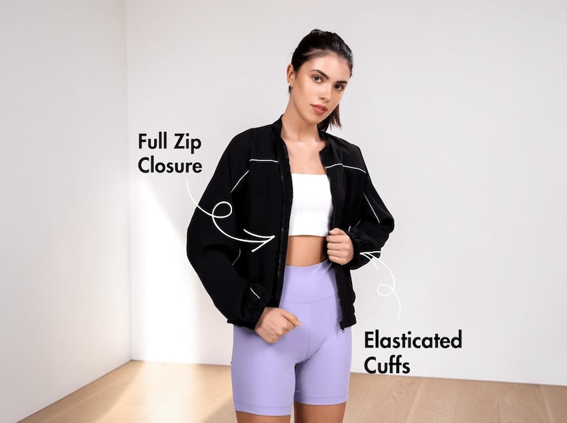 Pode incluir: Uma jaqueta preta com fecho de z&iacute;per completo e punhos el&aacute;sticos. A jaqueta &eacute; usada sobre um top branco e combinada com shorts lavanda. A imagem mostra as caracter&iacute;sticas da jaqueta.