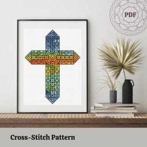 Könnte beinhalten: Kreuzstichmuster einer bunten Kreuz im Stil eines Buntglasfensters. Das Kreuz besteht aus kleinen Quadraten in Blautönen, Grüntönen, Gelb und Orange.