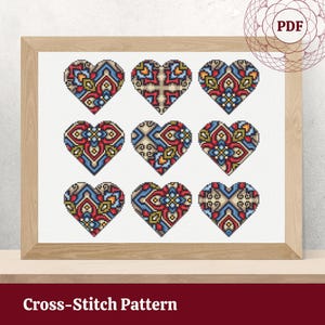 Può includere: Schema di punto croce con nove cuori colorati con intricati disegni geometrici in tonalità di rosso, blu e verde. Lo schema è incorniciato in una cornice di legno chiaro.