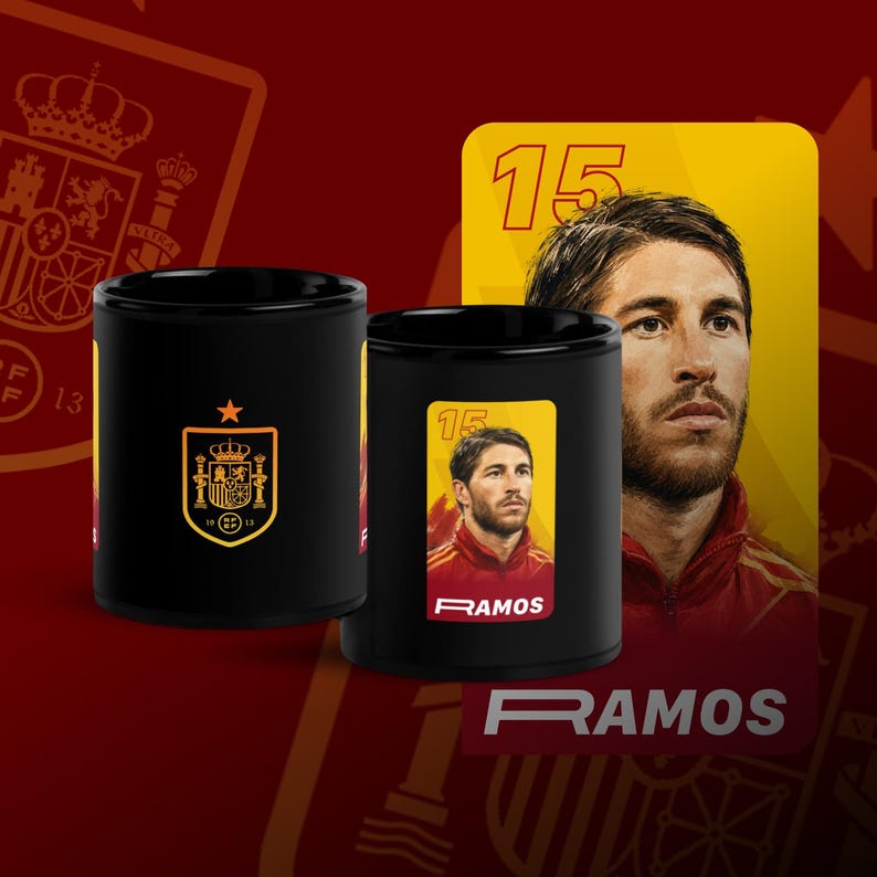 May include: Two black ceramic mugs featuring Spanish soccer player Sergio Ramos. One mug displays the Spanish coat of arms, while the other showcases a portrait of Ramos with the number 15. The word "RAMOS" is printed on the mug.