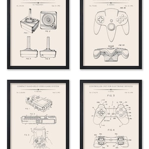 May include: Four framed patent prints of video game controllers. The prints feature detailed technical drawings of a joystick, a gamepad, a handheld console, and a modern controller, all in black and white.