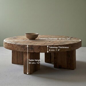 May include: A rustic, round coffee table made of reclaimed wood. The tabletop diameter is 24 inches, with a thickness of 1.5 inches. The table stands 12 inches tall. A small, brown bowl sits on the table. The table has a natural, weathered appearance.
