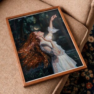 Peut inclure: Un cadre en bois rectangulaire contenant une impression représentant une personne aux longs cheveux auburn flottants, vêtue d'une robe blanche, tendant la main vers un orbe lumineux dans une forêt sombre sous un croissant de lune, avec des effets scintillants.