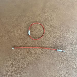 Peut inclure: Deux porte-cl&eacute;s rouges avec des fermoirs m&eacute;talliques sont pr&eacute;sent&eacute;s sur une surface marron imitation cuir. L'un est une boucle ferm&eacute;e, l'autre une ligne droite. Ces porte-cl&eacute;s sont probablement pour organiser des cl&eacute;s ou de petits objets.