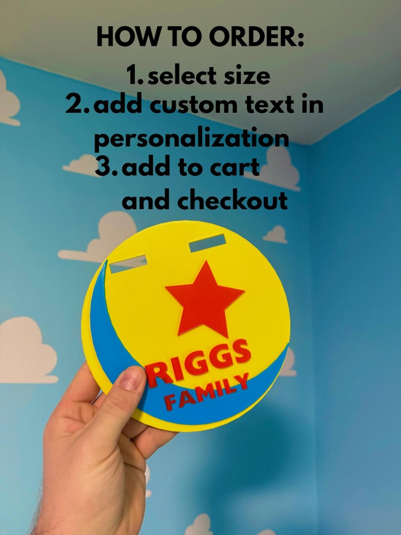 Peut inclure: Un panneau circulaire jaune et bleu avec une &eacute;toile rouge et le texte "RIGGS FAMILY". Le panneau comporte deux d&eacute;coupes rectangulaires et est tenu devant un mur bleu avec des d&eacute;calcomanies de nuages blancs. Le texte "HOW TO ORDER" et les instructions sont en haut.