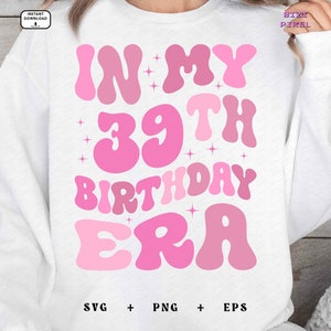 May include: A white sweatshirt with pink text that reads "In My 39th Birthday Era". The text is in a retro font style with stars around it. The sweatshirt also has the text "SVG + PNG + EPS" at the bottom.