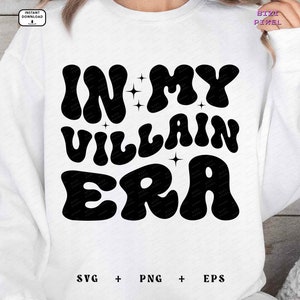 May include: White sweatshirt with black text that reads "In My Villain Era" in a retro font. The text is surrounded by small stars.
