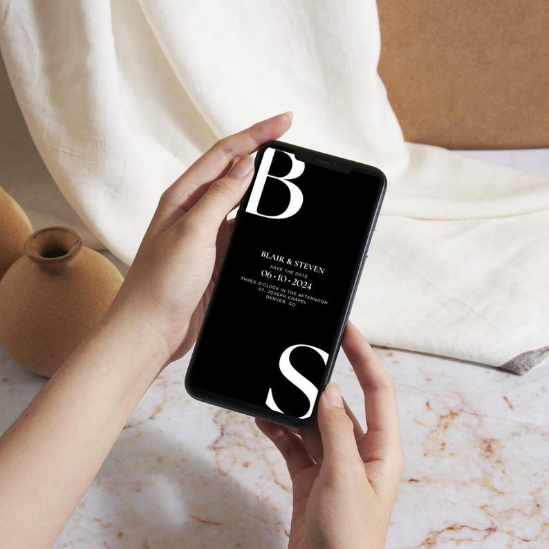 May include: A black and white save the date card on a smartphone screen. The card features the text "Blair & Steven" and the date "06-10-2024".