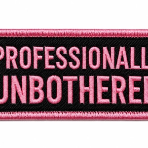 May include: A rectangular embroidered patch with a black background and a pink border. The text "PROFESSIONALLY UNBOTHERED" is stitched in pink capital letters across the center of the patch, featuring a clean, bold, sans-serif font style.