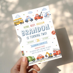 May include: A rectangular birthday invitation card featuring watercolor illustrations of various vehicles including a school bus, police car, tow truck, helicopter, garbage truck, car, excavator, and fire truck, with text reading HONK, BEEP, VRUUUM BRANDON IS TURNING TWO!