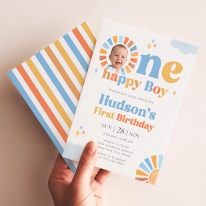 May include: A first birthday invitation card featuring a photo of a baby inside a sun graphic, with the text One happy Boy, Hudson's First Birthday, and event details. The card has blue, orange, and yellow accents and a striped envelope back.