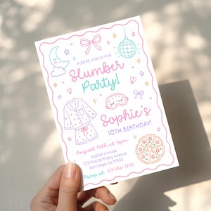 May include: A rectangular invitation card with a pink wavy border featuring line art of a moon, bow, disco ball, pajamas, sleep mask, and pizza. Text reads: Please join us for Slumber Party! Sophie's 10th Birthday! August 14th at 5pm.